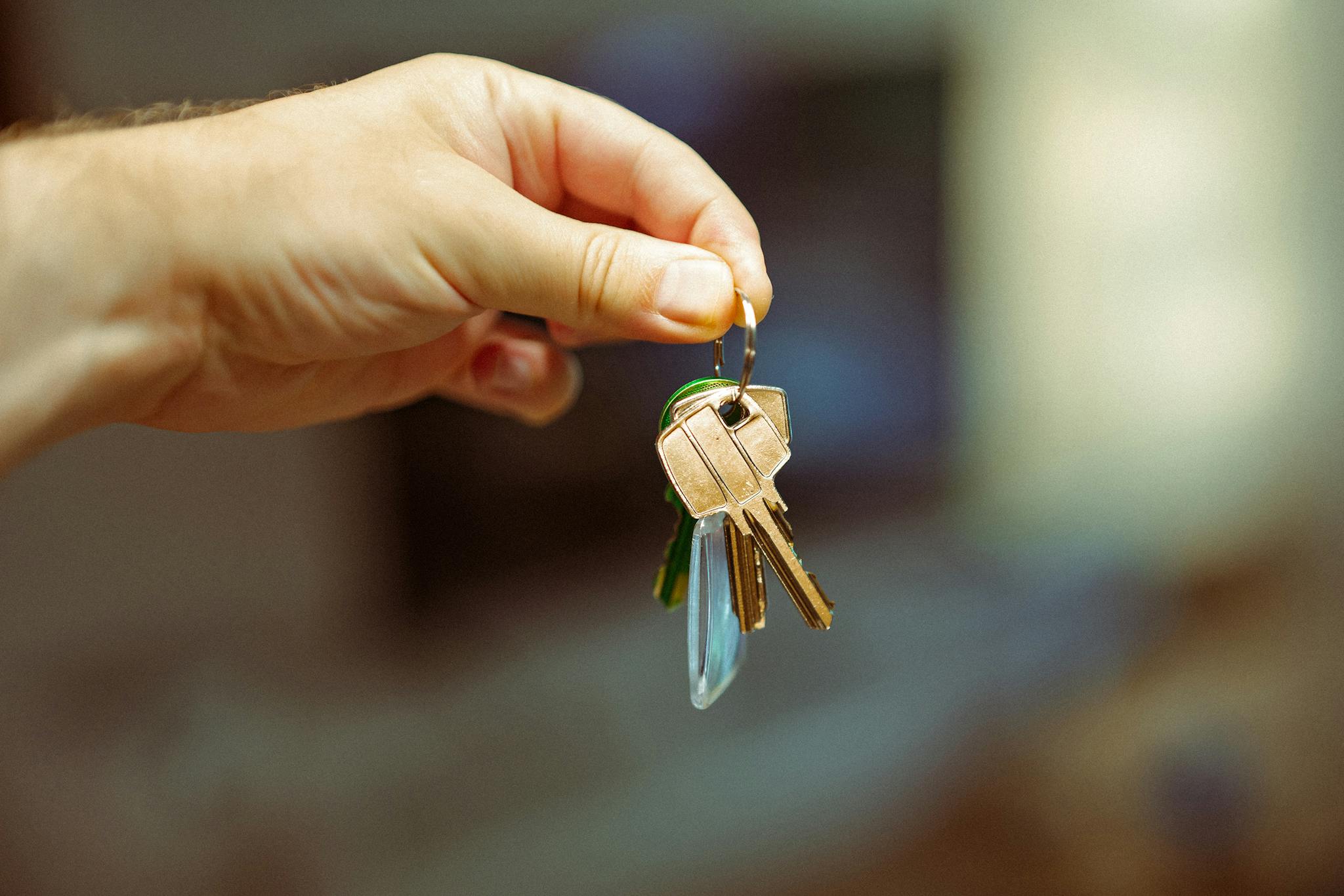 A close-up image of a hand holding a keyring with several house keys, symbolizing real estate and home ownership.